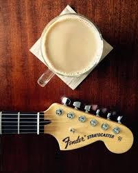 A Fender Telecaster resting on a table with a coffee cup